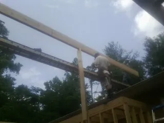 Carpenter setting a ridge beam over a new addition frame — Ice Dam Removal by Roofing Brothers in Loretto