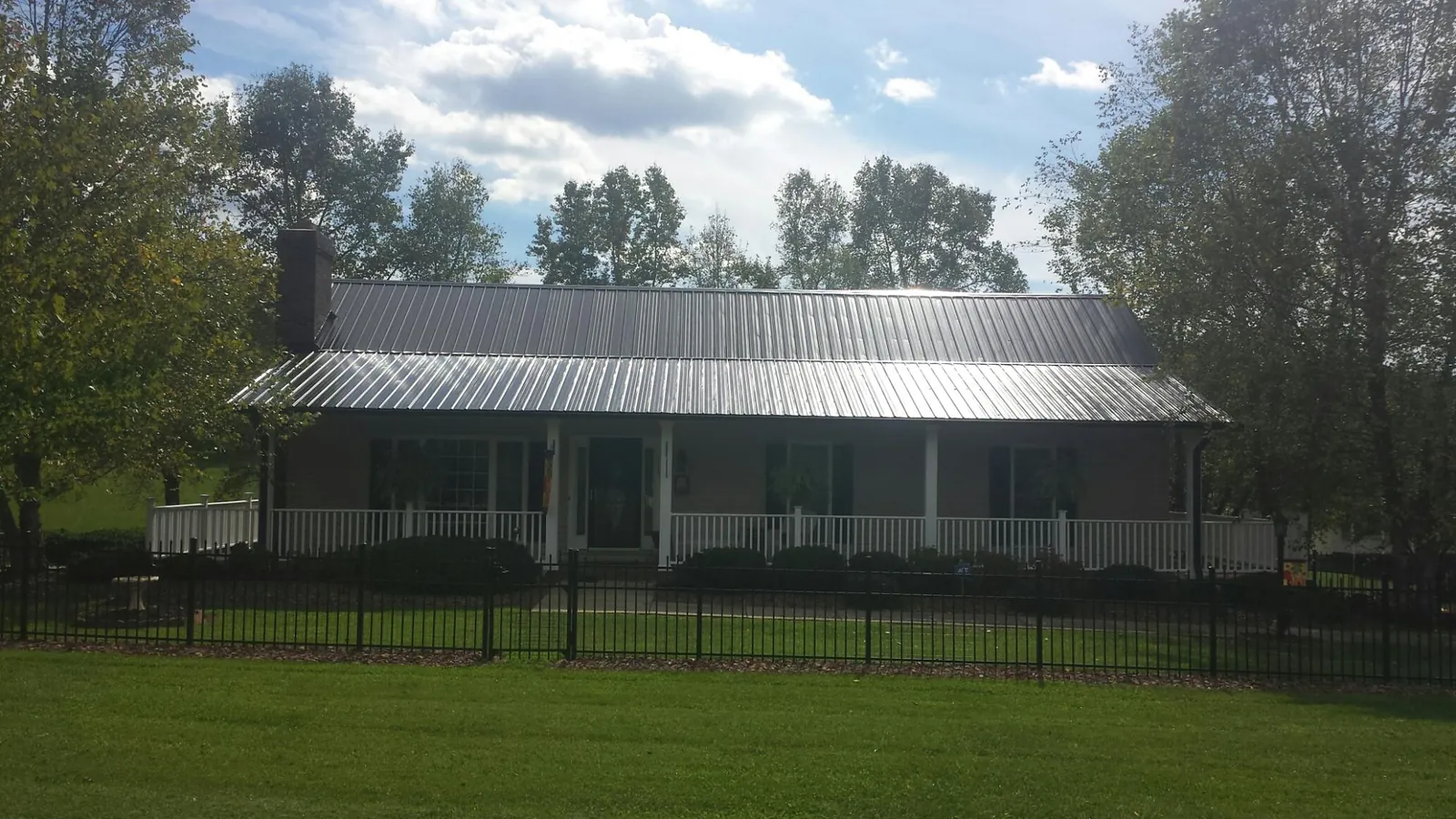 Gray metal roof on a brick ranch with a full width front porch — Gutter Guard Installation work by our crew in Loretto