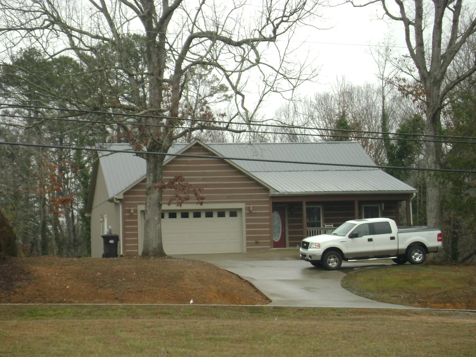 Gray metal roof on a log sided house with an attached two car garage in Loretto